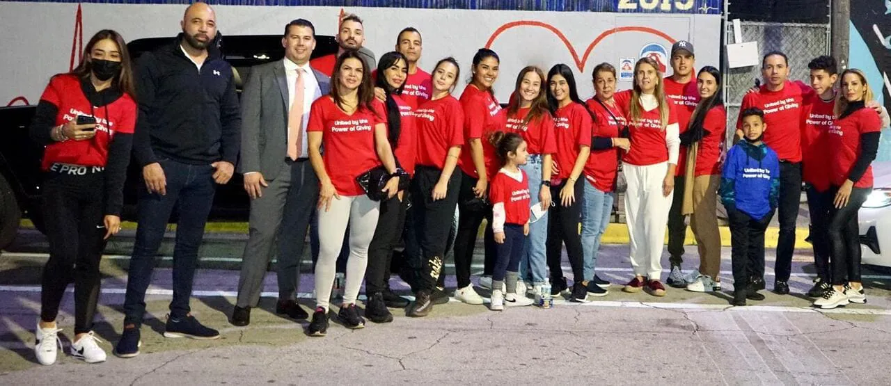 Voluntarios de United by the Power of Giving distribuyendo donaciones en Miami durante el evento anual de apoyo a person